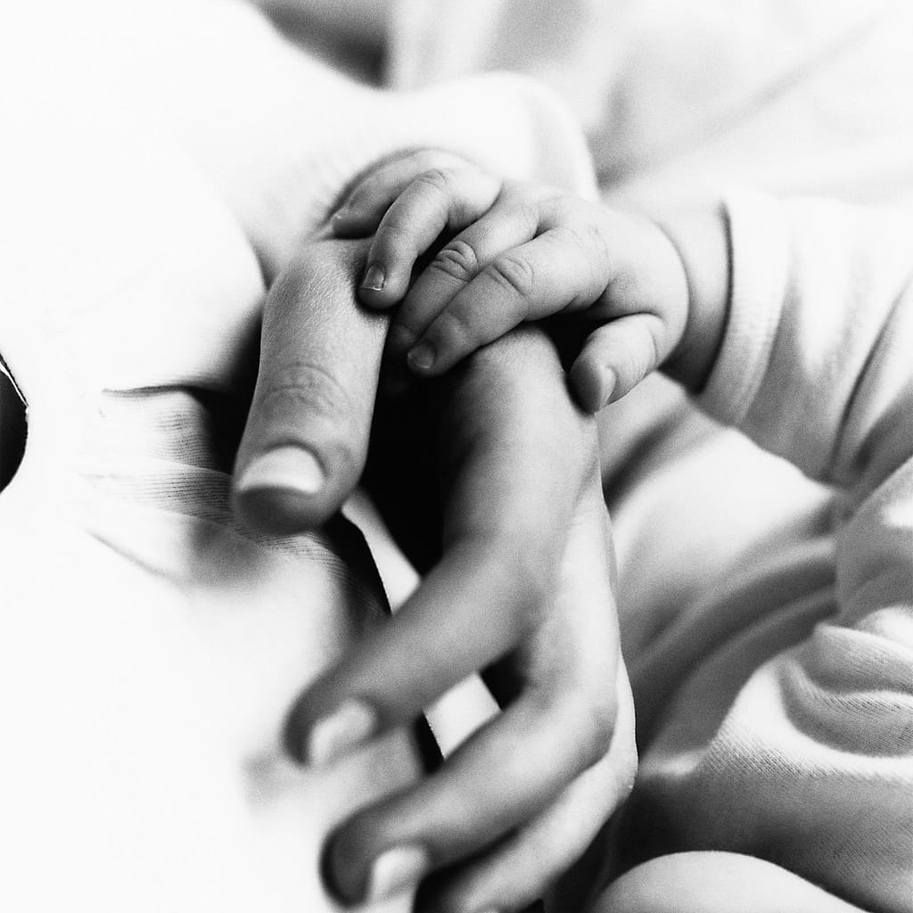 Baby haelt sich an Mamas Hand beim Baby Fotoshooting fest