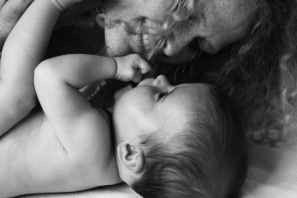Baby und Mama kuscheln zusammen und Baby spielt mit den Haaren seiner Mutter beim Baby Fotoshooting in Reinbek bei Hamburg