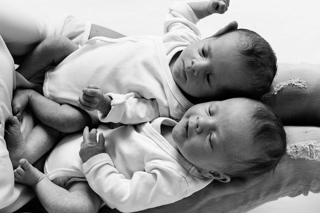Zwillinge nebeneinander auf den Beinen der Mutter liegend beim Baby Fotoshooting in Hamburg Barmbek