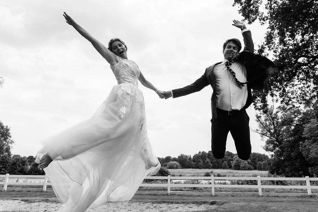 Das Hochzeitspaar springt vor Freude gemeinsam in die Luft am Goldschätzchen der Koch Fabrik auf dem Golf Park Peiner Hof in Priesdorf beim Hochzeitsfotograf Hamburg