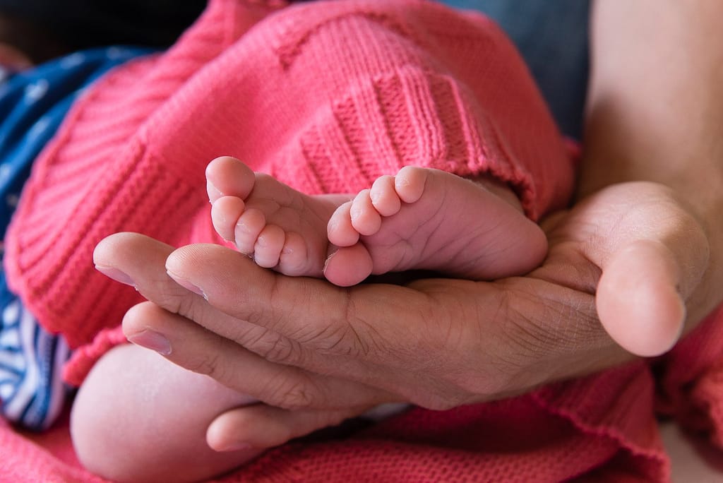 Close-up von den Babyfüssen in der Hand vom Papa beim Baby Fotoshooting zuhause in Hamburg Stellingen