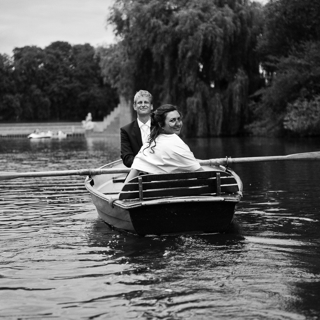 Freudiges Hochzeitspaar im romantischen Ruderboot auf dem Stadtparksee in Hamburg Winterhude bei den Brautpaarfotos beim Hochzeitsfotograf Hamburg