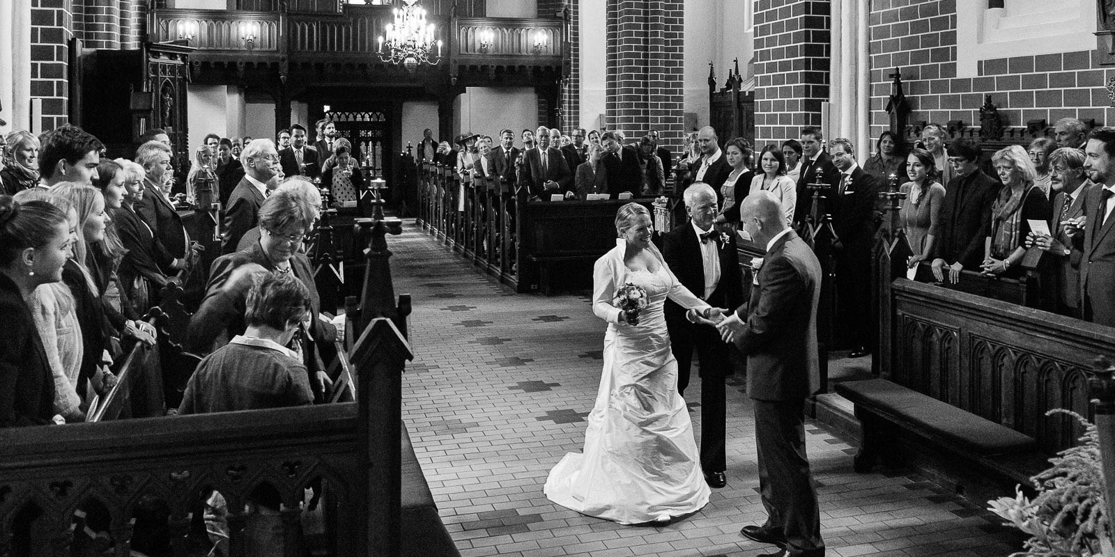 Brautvater übergibt die Braut dem Bräutigam vor der Trauung in der Sankt Marien Kirche in Röbel an der Müritz in Mecklenburg Vorpommern beim Hochzeitsfotograf Hamburg