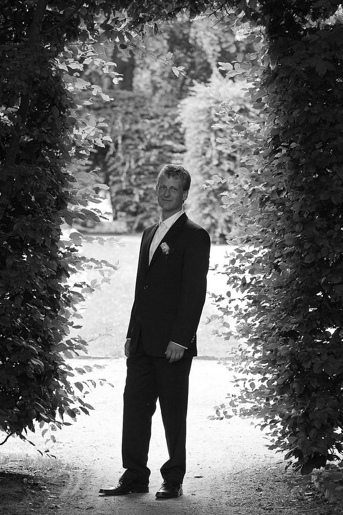 Der Bräutigam posiert für seine Braut im Adam und Eva Heckengarten im Hamburger Stadtpark in Winterhude bei den Brautpaarfotos beim Hochzeitsfotograf Hamburg