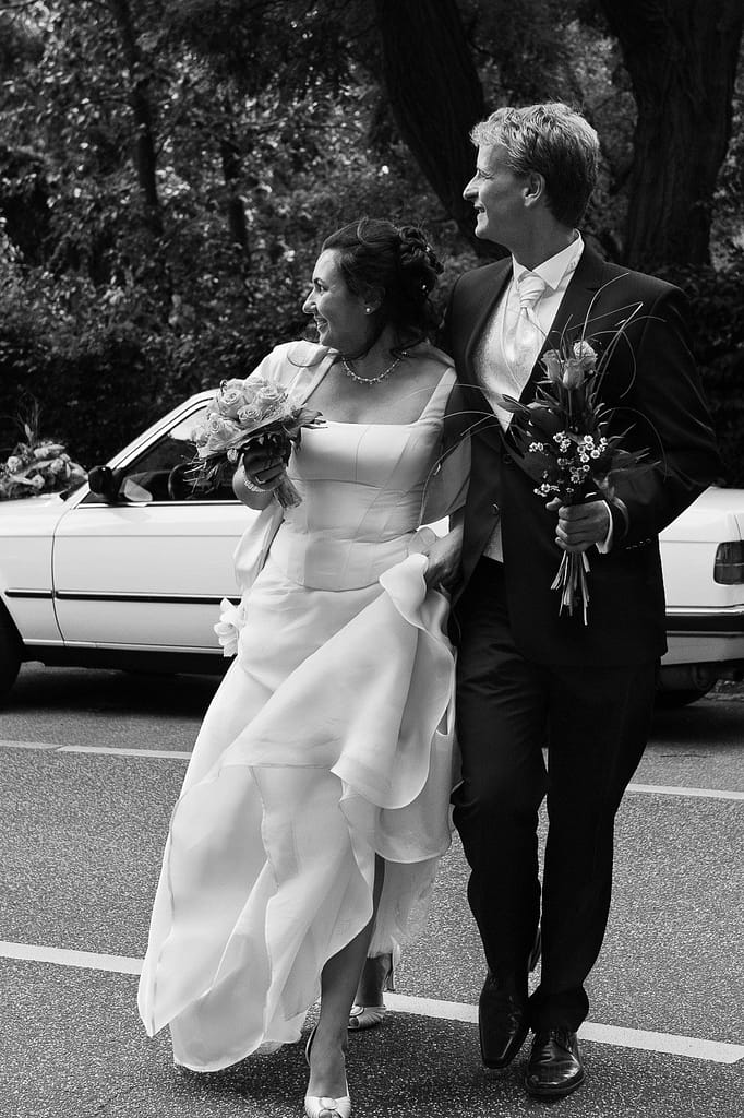 Hochzeitspaar überquert die Straße auf dem Weg zur Liebesinsel am Stadtparksee im Hamburger Stadtpark bei den Brautpaarfotos beim Hochzeitsfotograf Hamburg
