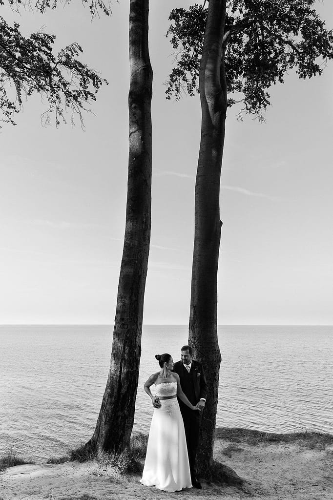 Hochzeitspaar posiert am Steilufer im Buchenwald am Weissenhäuser Strand vor der weiten Ostsee beim Hochzeitsfotograf Hamburg