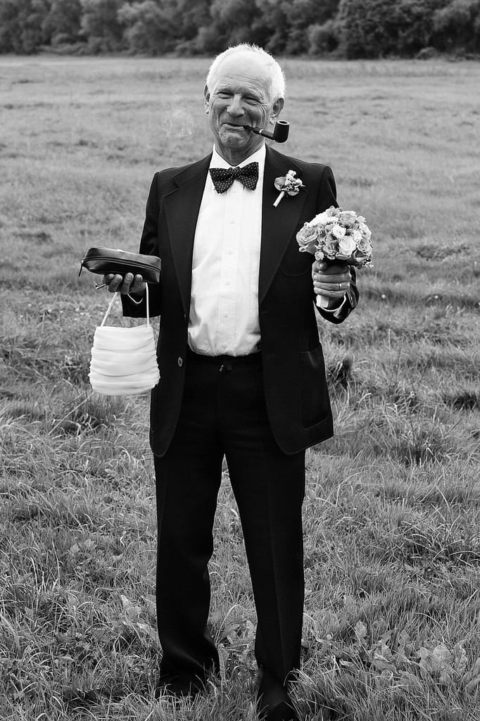 Brautvater hält den Brautstrauß der Braut bei den Hochzeitsfotos im Park vom Gutshof Woldzegarten in Mecklenburg Vorpommern beim Hochzeitsfotograf Landhochzeit Hamburg
