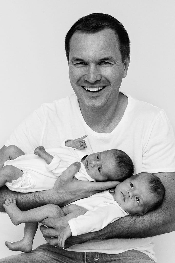 Lachender Vater hält beide Zwillinge im Arm beim Baby Fotoshooting in Hamburg Barmbek