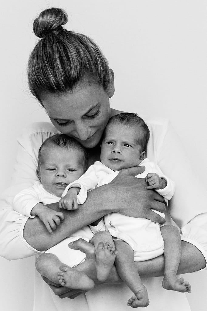 Mama hält ihre Zwillinge im Arm und kuschelt mit ihnen beim Baby Fotoshooting in Hamburg Barmbek