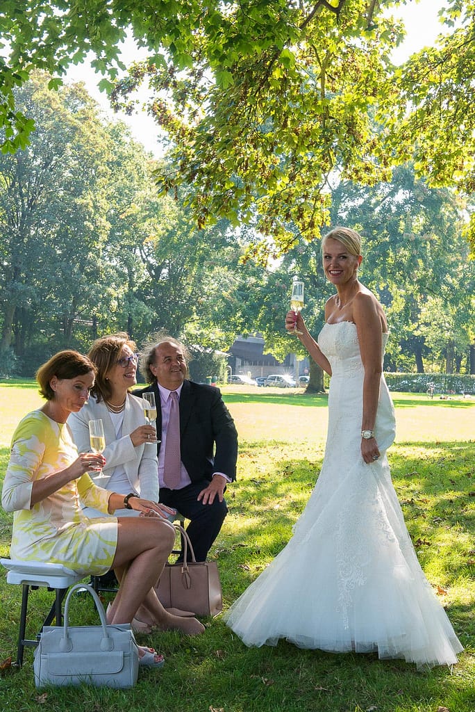 Die Braut mit ihren Hochzeitsgästen beim Sektempfang im Seelemannpark an der Eppendorfer Hochzeitskirche beim Hochzeitsfotograf Hamburg