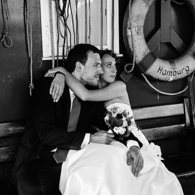 Die Braut umarmt ihren Bräutigam auf den historischen Kaianlagen vom Hafenmuseum Hamburg im Hansahafen beim Hochzeitsshooting mit dem Hochzeitsfotograf Hamburg