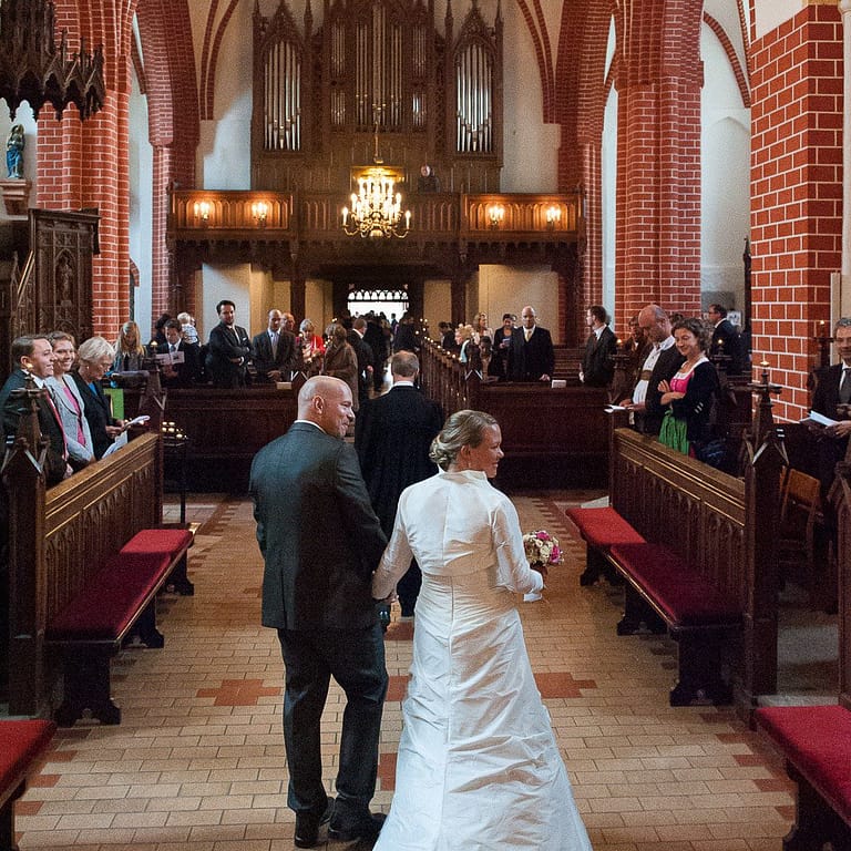 Hochzeitspaar Hand in Hand beim Auszug aus der Sankt Marien Kirche in Röbel an der Müritz in Mecklenburg Vorpommern beim Hochzeitsfotograf Landhochzeit Hamburg