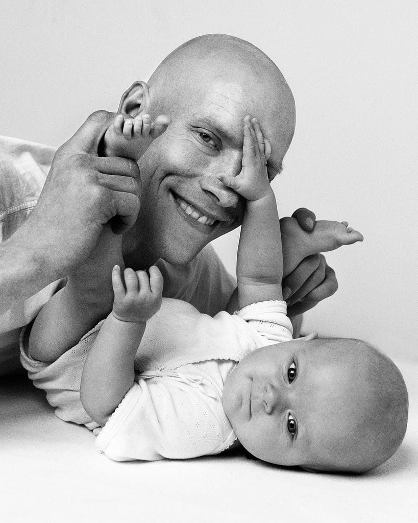 Baby greift Papa mit den Händen ins Gesicht beim Baby Fotoshooting in Hamburg Winterhude