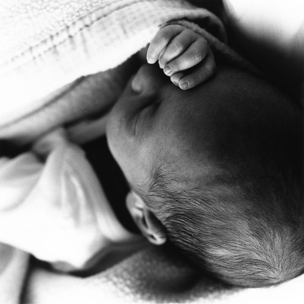 Schlafendes Baby mit der Babyhand vor dem Babygesicht bei der Neugeborenenfotografie in Hamburg Sasel