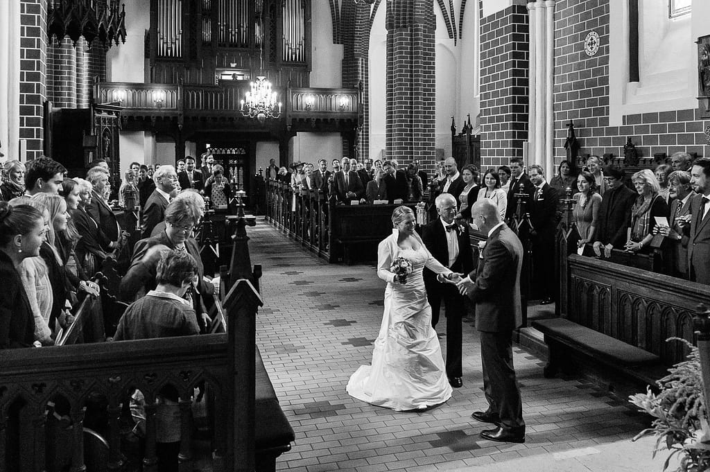 Brautvater übergibt die Braut dem Bräutigam vor der Trauung in der Sankt Marien Kirche in Röbel an der Müritz in Mecklenburg Vorpommern beim Hochzeitsfotograf Landhochzeit Hamburg