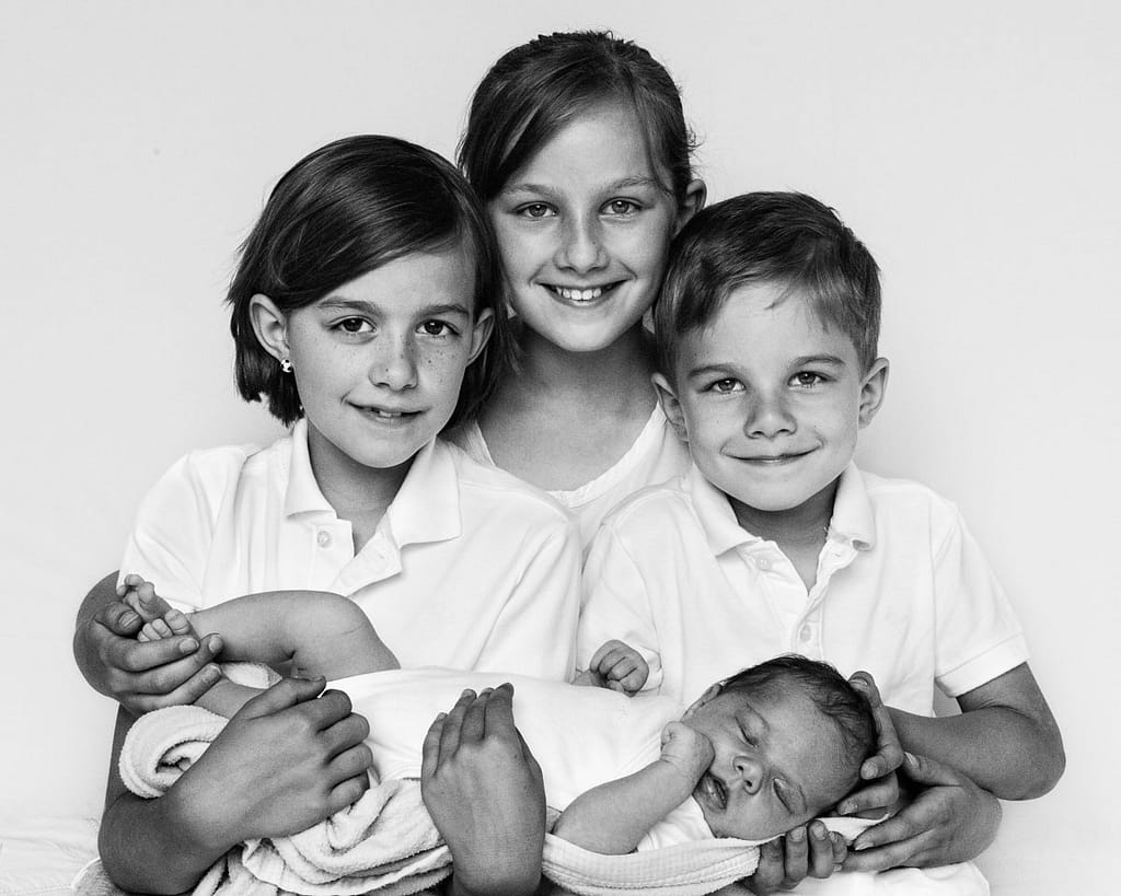 Drei Geschwister halten das Baby beim Baby Foto Shooting in Hamburg