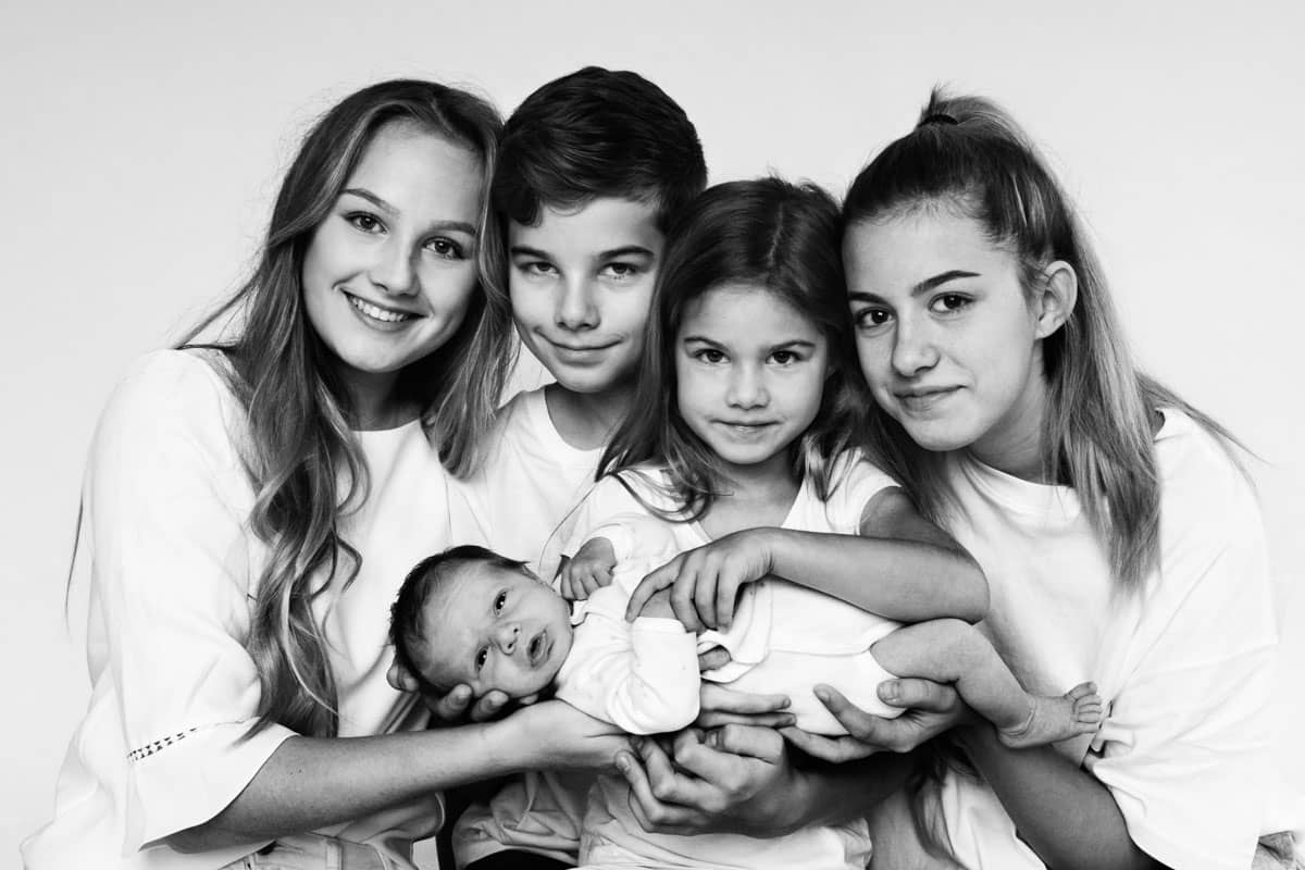 Vier Geschwister halten das Baby beim Baby Foto Shooting in Hamburg