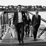 Der Bräutigam führt seine Hochzeitsgäste vom Anleger Bubendeyufer an der Elbe zur Villa im Jachthafen bei Hochzeitsfotografie Hamburg