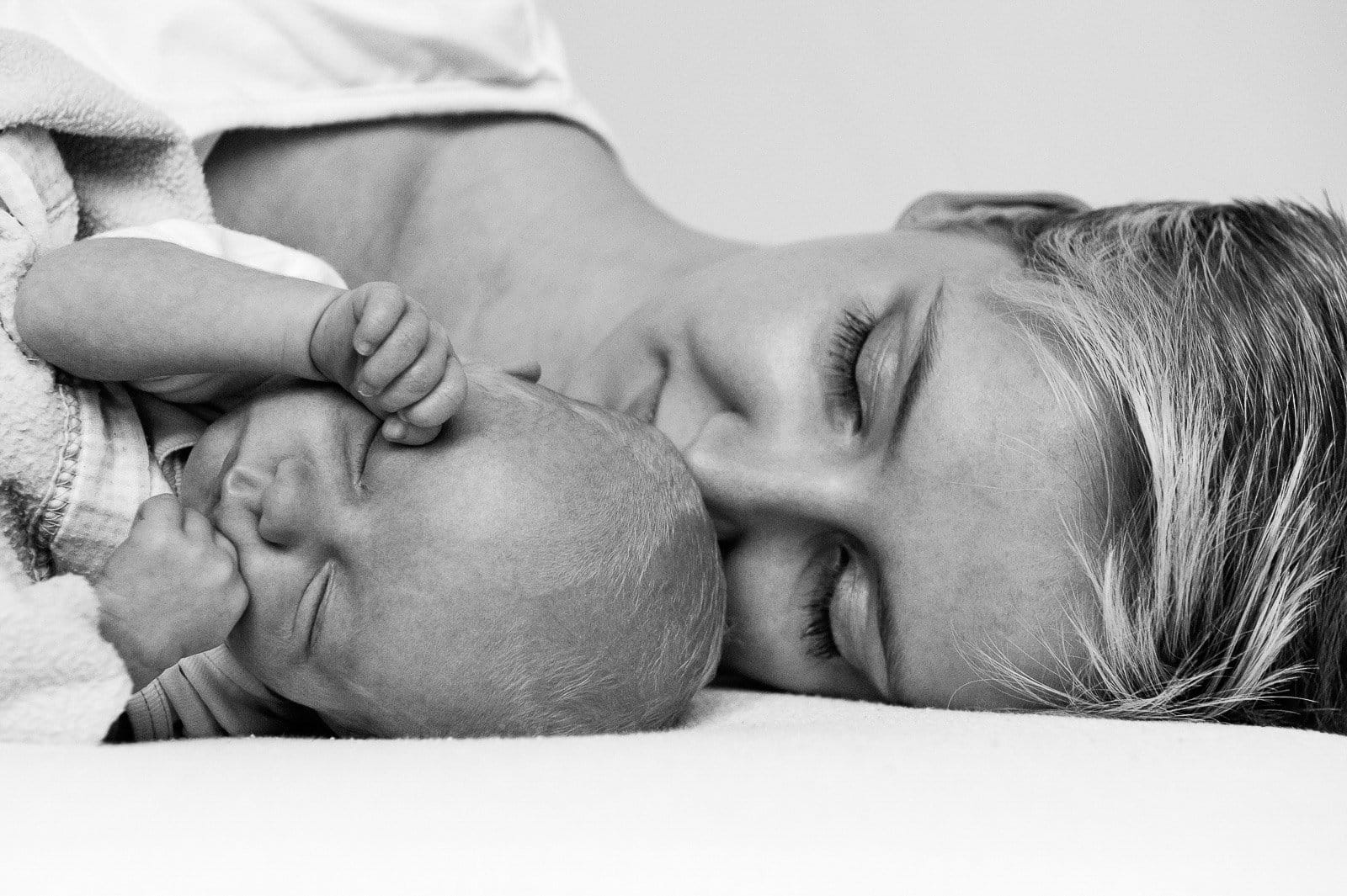 Mama und Baby liegen zusammen gekuschelt auf dem Bett beim Baby Fotoshooting in Hamburg Harburg