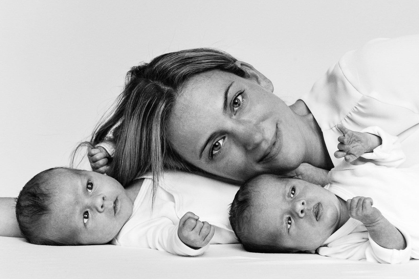 Mama und ihre Zwillinge liegen gemeinsam auf der Tagesdecke beim Baby Fotoshooting in Hamburg Barmbek