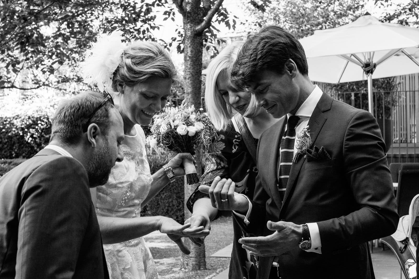 Braut, Bräutigam und Hochzeitsgäste begutachten die Hochzeitsringe beim Hochzeitsfotograf Hamburg