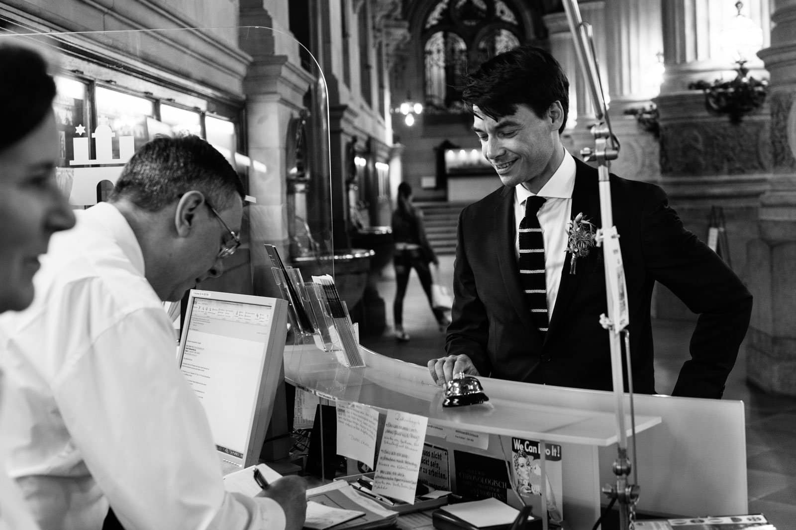 Der Bräutigam entrichtet an der Rezeption der Empfangshalle vom Hamburger Rathaus die Gebühren für die Trauung im Phönixsaal beim Hochzeitsfotograf Hamburg