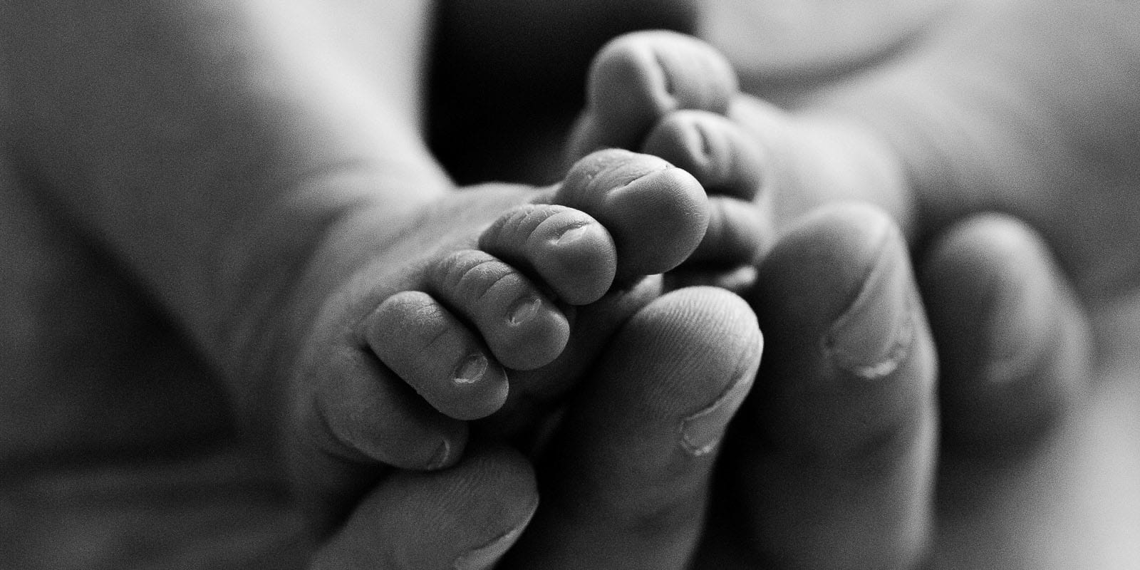 Babyfüsse in Papas Hand bei der Neugeborenenfotografie in Hamburg Harburg