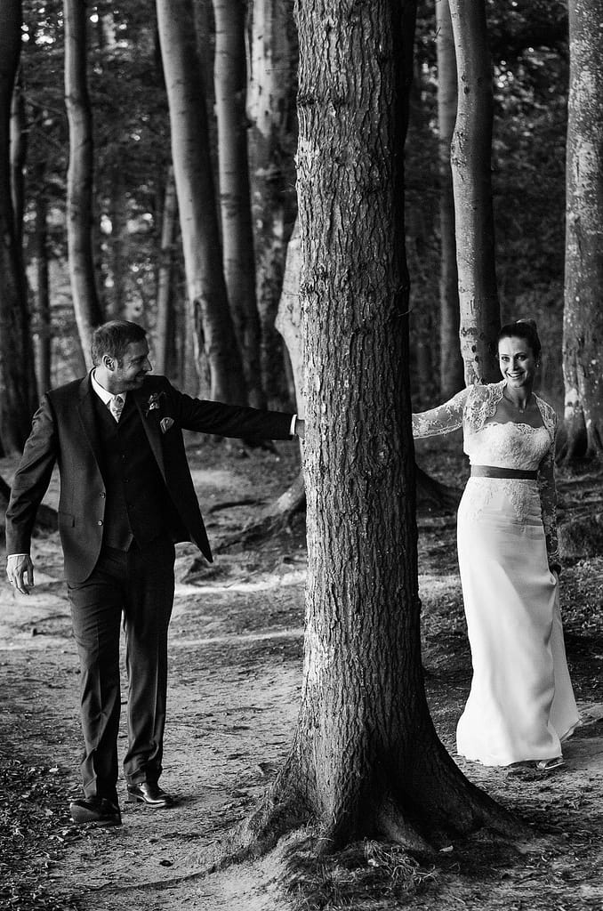 Braut und Bräutigam schlendern gemeinsam um die Bäume im märchenhaften Gespensterwald am Weissenhäuser Strand an der Ostsee beim Hochzeitsfotograf Hamburg