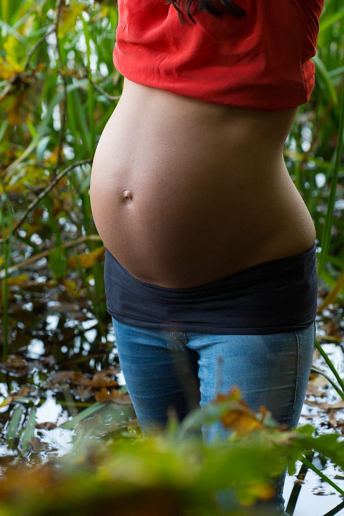 Schwangere steht im Schilf am Seeufer beim Babybauch Shooting in Hamburg draußen in der Natur