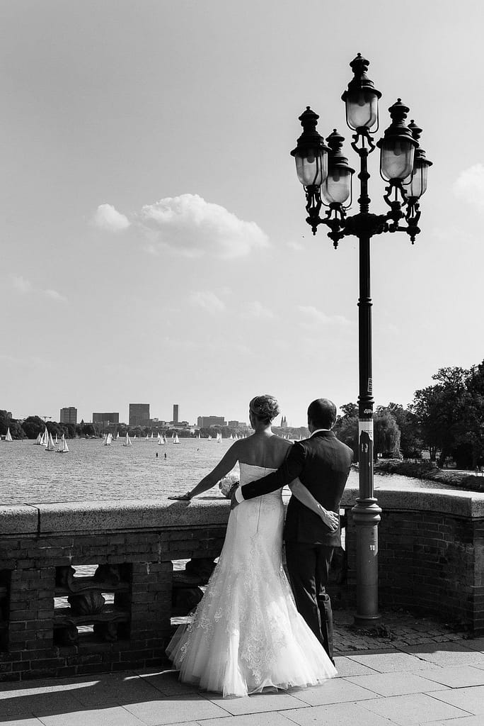 Braut umd Bräutigam Arm in Arm auf der Krugkoppelbrücke in Harvestehude mit Blick auf die Außenalster beim Hochzeitsfotograf Hamburg