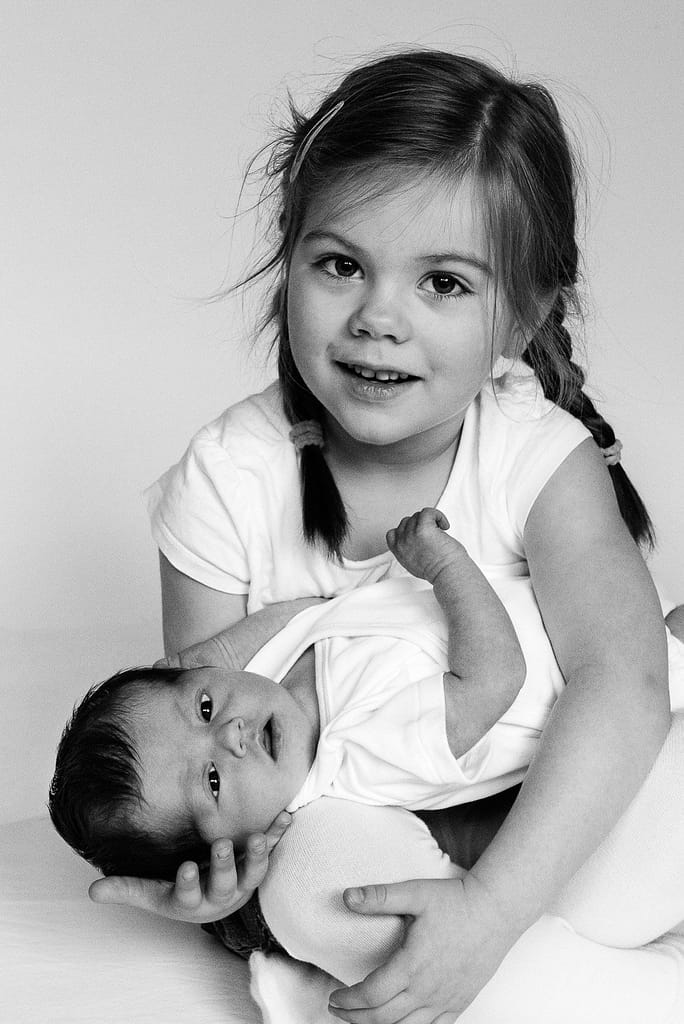 Kleine Schwester hält Baby im Arm beim Baby Fotoshooting in Hamburg Barmbek