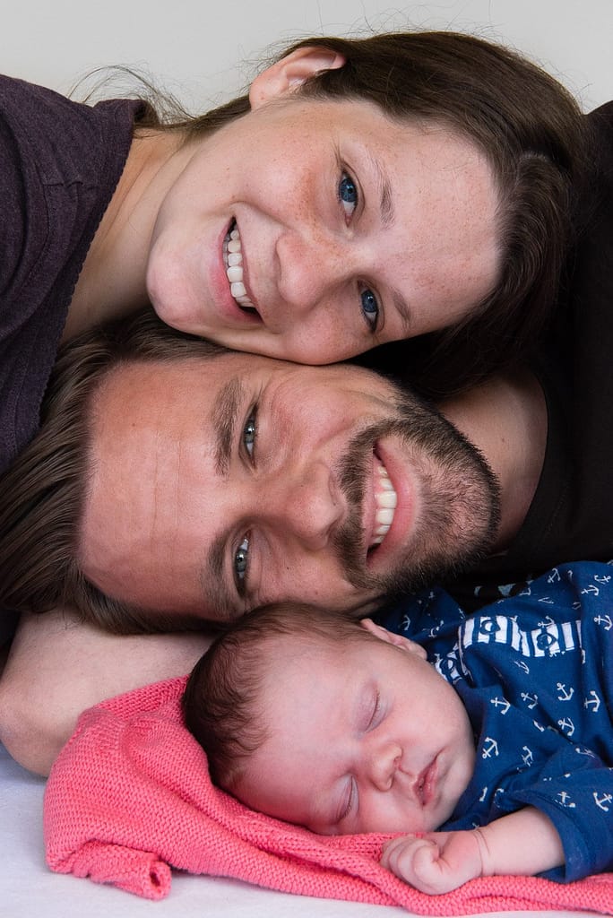 Lachende Familie mit schlafenden Baby beim Baby Fotoshooting zuhause in Hamburg Othmarschen