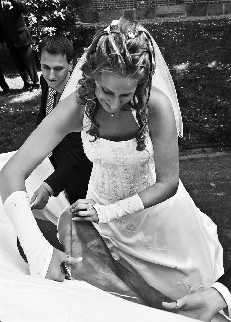 Hochzeitspaar beim Ausschneiden von einem Herz aus einem Bettlaken nach der Trauung vor der Kirche beim Hochzeitsfotograf Hamburg