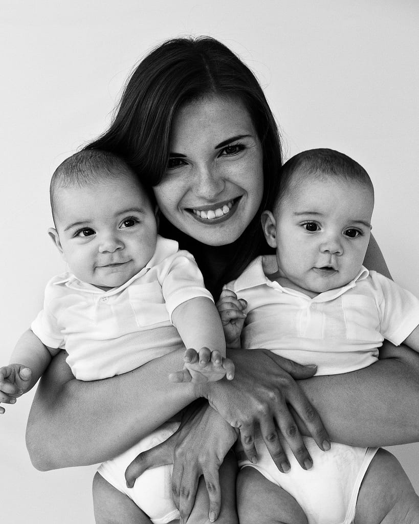 Mama hält beide Zwillinge im Arm und lächelt beim Babyfotograf in Hamburg Harvestehude